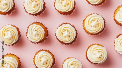 A flat lay of decorated cupcakes with swirled frosting on a pink background.