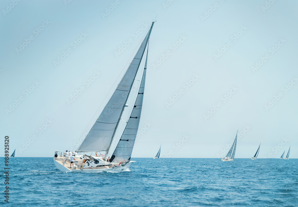 Fototapeta premium Sailboats races near Brindisi under blue sky. Crew members working together on deck