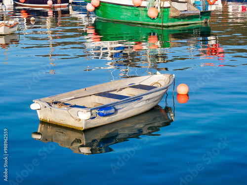 Colourful small boats reflected in calm harbour waters on a September morning photo