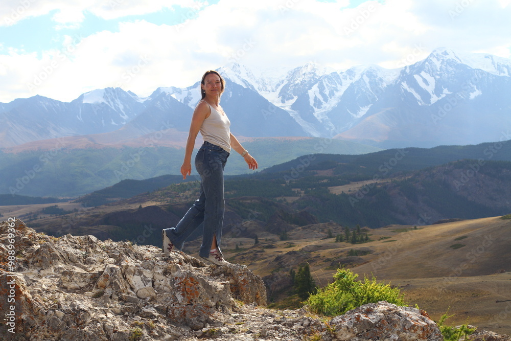 Hiker woman on top Aktash Altai mountains. Scenic view and snowy tops on background. Hiker woman on top Aktash Altai mountains. Scenic view and snowy tops on background.