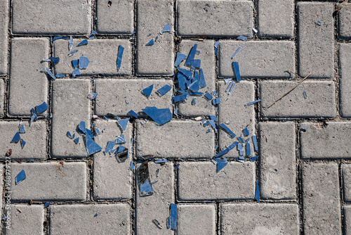 
A close-up shot of shattered glass scattered on a gray brick pavement. Conceptual purposes related to danger, fragility, or brokenness. photo