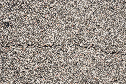 This photo shows a cracked concrete surface covered with small white pebbles, providing a textured background for your design projects.