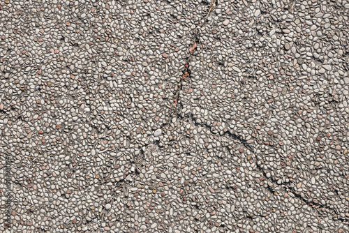 This photo shows a cracked concrete surface covered with small white pebbles, providing a textured background for your design projects.