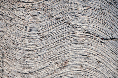 This high-resolution image captures the intricate details of weathered concrete, featuring a unique pattern of curved lines and subtle cracks. Ideal for design projects, website backgrounds, or creati