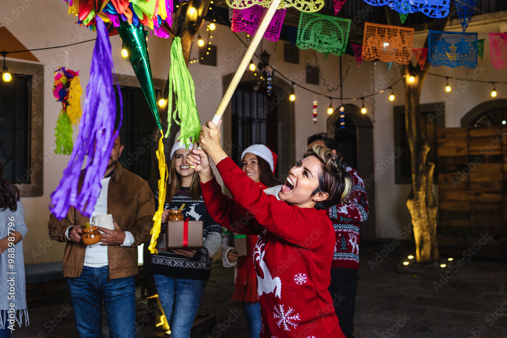 © Marcos - Mexican woman and family breaking a piñata at traditional posada party for Christmas in Mexico Latin America, hispanic people