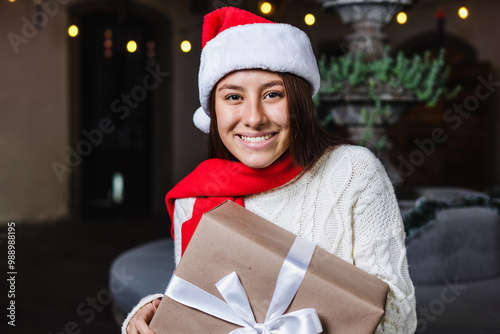 Hispanic young woman portrait holding a gif box at traditional posada party for Christmas in Mexico Latin America