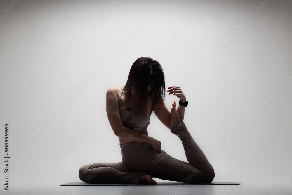 Fototapeta premium Beautiful caucasian woman in yoga pose. Half silhouette shot of a girl making stretching exercises.