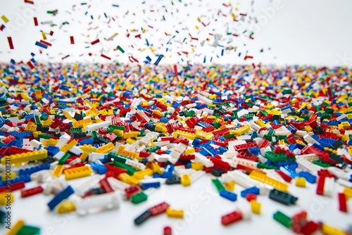 Hundreds of brightly colored plastic blocks scattered across a smooth white floor, creating a chaotic yet harmonious abstract pattern.  photo