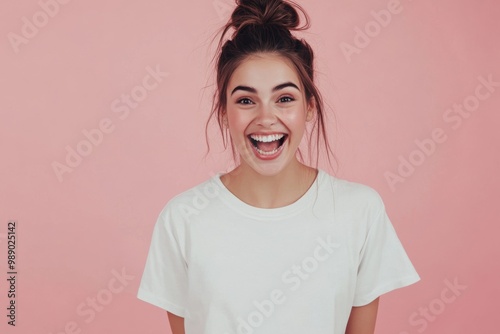 Happy young woman laughing in white t-shirt, pink backdrop