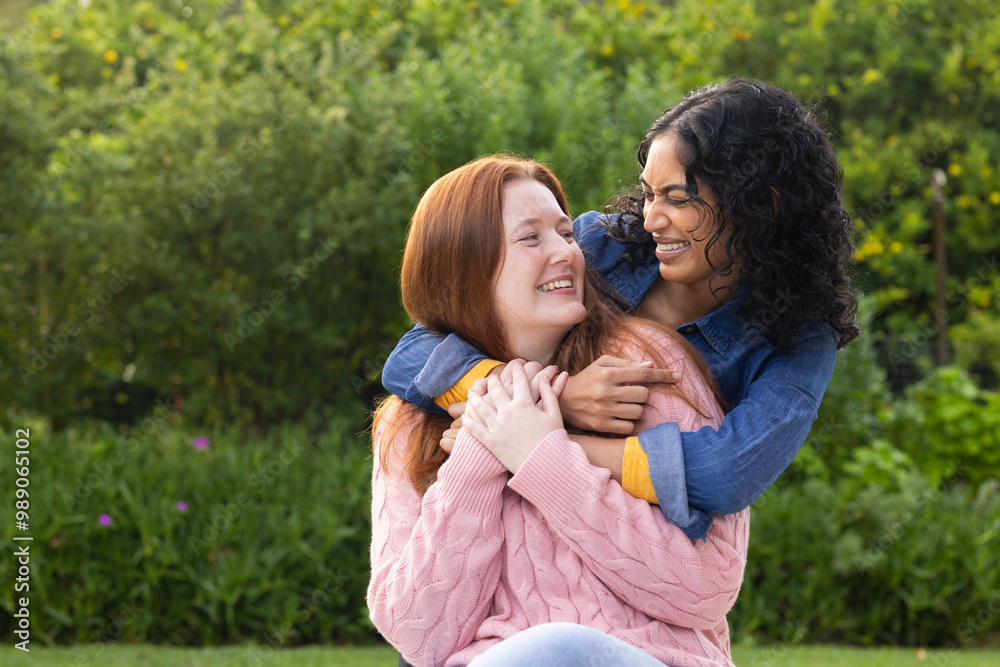 Hugging and laughing, two women friends enjoying time together outdoors in park Hugging and laughing, two women friends enjoying time together outdoors in park