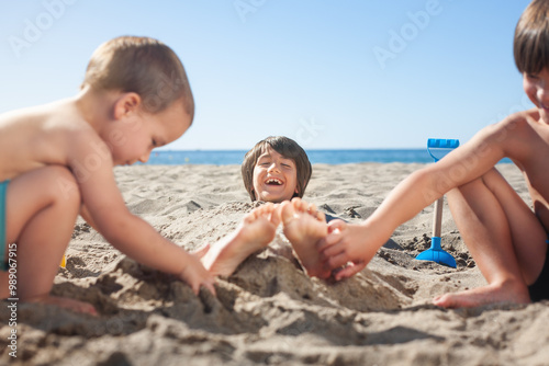 Photos Child laughing when other children tickle his feet at the beach