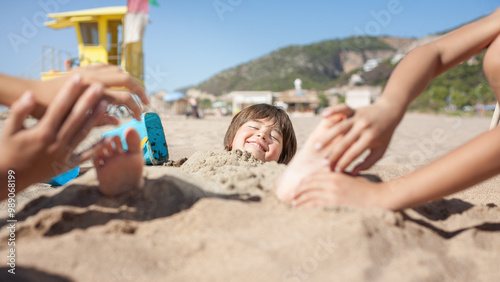 Obraz na plátně Sand-covered boy smiles as hands tickle the soles of his feet.