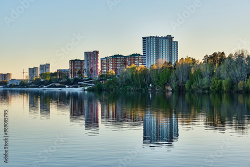 Residential buildings and embankment of town Krasnokamsk, Russia. View from Kama River at sunset