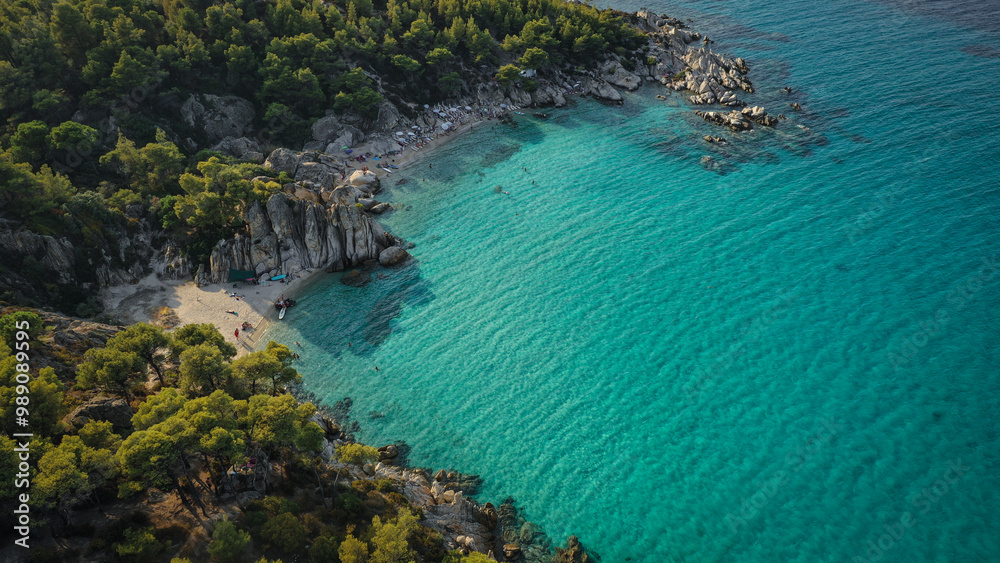 Obraz premium Paradise Found: A hidden beach cove where the turquoise waters meet the rugged cliffs, offering the perfect summer escape in Greece