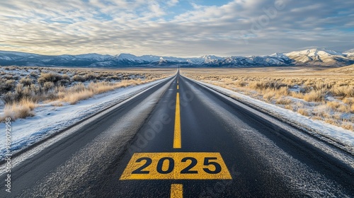 Long road leading to mountains with 2025 on asphalt during winter