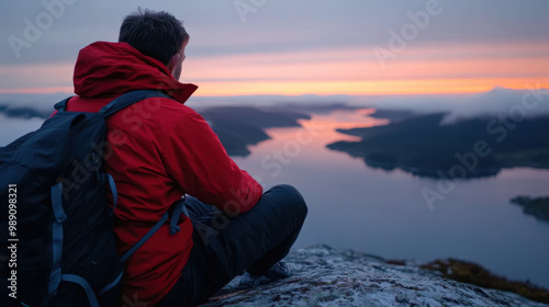 personne assise sur un rocher qui contemple le couché du soleil dans un fjord photo