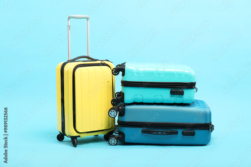 Different bright suitcases on light blue background