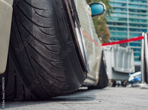 Low profile tire on a modified car parked at a city event showcasing automotive culture during daytime