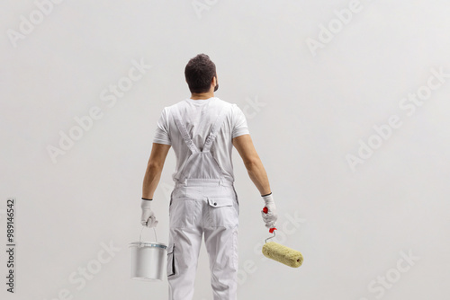 Rear view shot of a painter holding a bucket and a paint roller