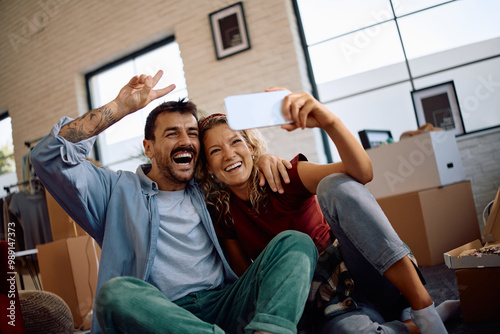 Cheerful couple taking selfie in their new home. photo