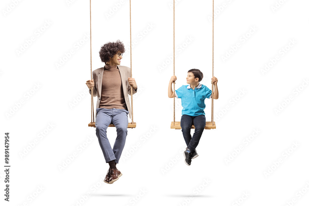 Young man and a boy sitting on wooden swings Young man and a boy sitting on wooden swings