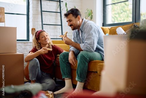 Happy couple talking while eating pizza for lunch in their new home. photo