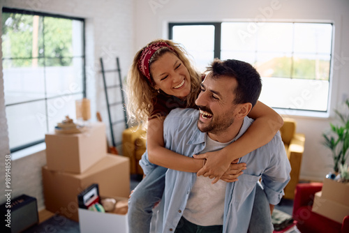 Cheerful couple piggybacking in their new home.