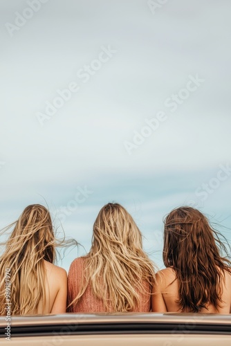 Three friends enjoying a scenic view, hair blowing in the wind, carefree summer vibe. photo