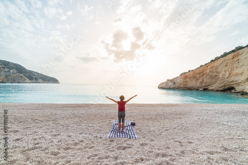 Woman performing yoga exercises on a beautiful empty beach in Greece. Dramatic coastline scenic bay rocky cliffs in the Ionian islands.