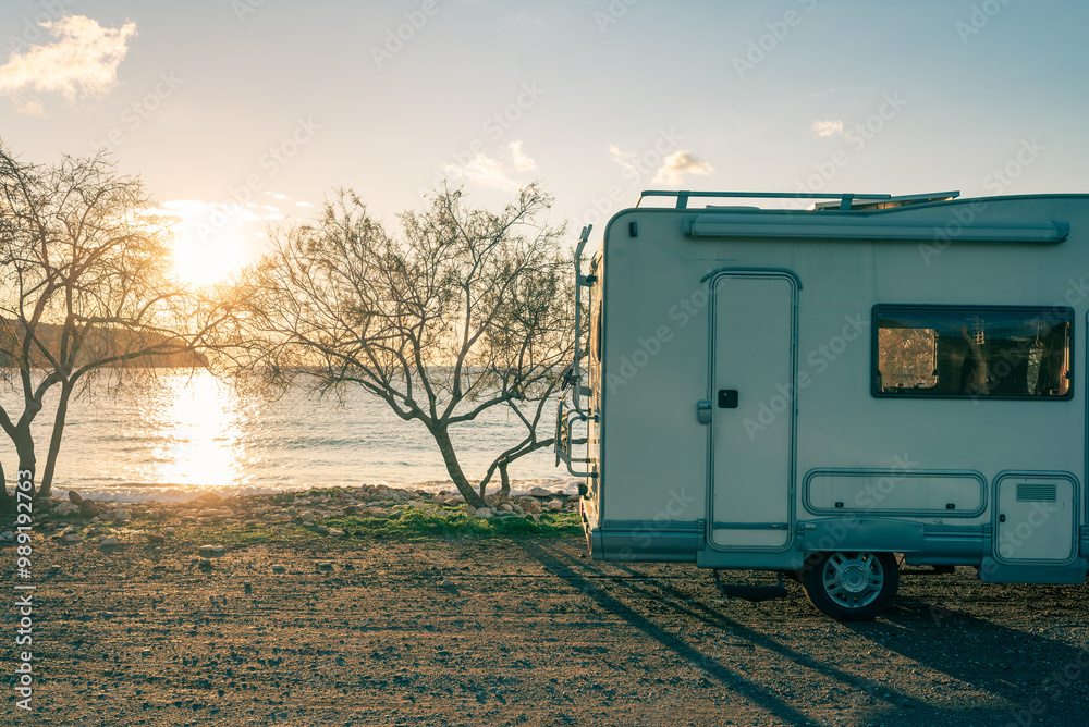 Coastal sunset with recreational vehicle, Motorhome parked by the seaside under a dramatic sunset sky