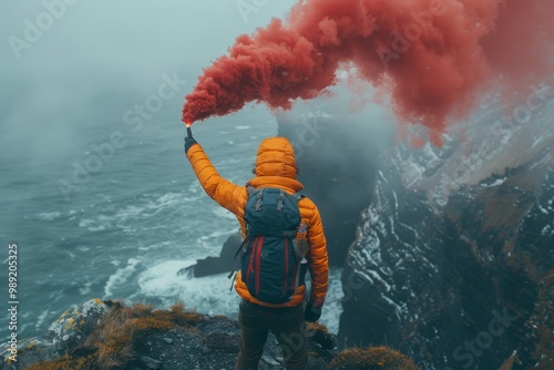 Distress signal  man in orange vest uses red smoke bomb on rocky island with gray clouds