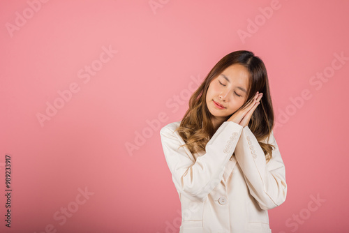 Portrait Asian beautiful young woman pretended emotions sleeping tired eyes closed dreaming with hands together near face, studio shot on pink background, with copy space, insomnia concept