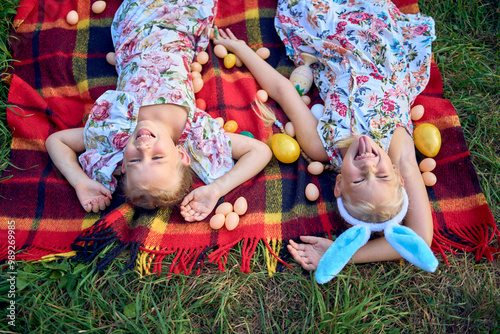 little girls, sisters, playing on a picnic blanket with eggs after an Easter egg hunt photo