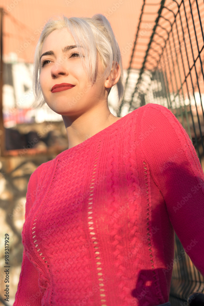 Fototapeta premium Smiling young woman by a gate in urban setting