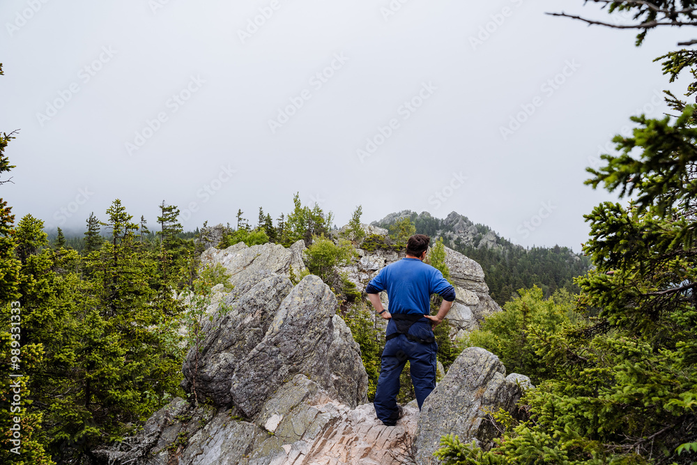 Naklejka premium A Hiker Enjoys the View Overlooking Majestic Misty Mountain Peaks in a Beautiful and Serene Natural Landscape Surrounded by Nature