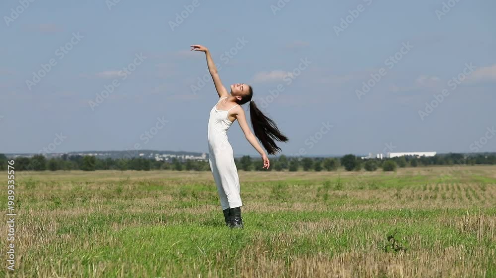 Young beautiful girl in a long white dress dancing on a mown field Young beautiful girl in a long white dress dancing on a mown field