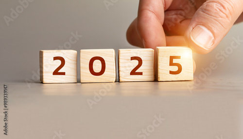 Hand Turning Wooden Cubes from 2024 to 2025, New Year Concept with Glowing Light, Stock Image for Business, Year-End Reviews, Future Planning, and Inspirational Content for Blogs or Websites.