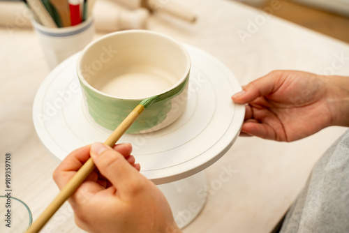 Girl is making a colorful decoration of a clay project with paint and water. Painting ceramic products using acrylic paint and brush. photo