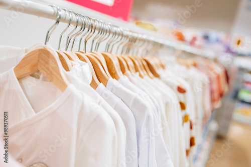 Beautiful baby clothes hanging arranged on rack in a modern store or shop. Shopping interior concept. No people. photo