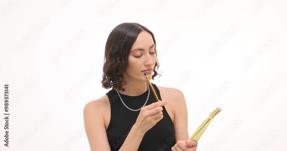 Thoughtful young woman makes notes writing in paper notepad on white background. Inspired brunette female records ideas preparing for business meeting Thoughtful young woman makes notes writing in paper notepad on white background. Inspired brunette female records ideas preparing for business meeting