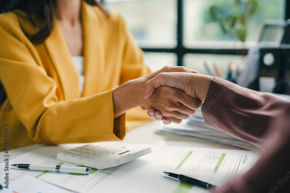 © amnaj - Businesswomen shaking hands after reaching an agreement on a deal during a meeting at the office