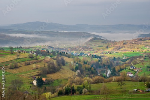 Rural landscape with fields, meadows, small villages, sensitively and ecologically managed landscape, in the background mountains after a storm with fog.