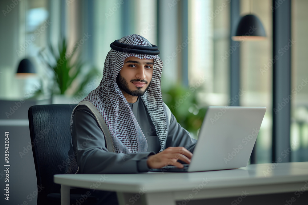 Young arab businessman or employee in traditional outfit working at the table in office Young arab businessman or employee in traditional outfit working at the table in office