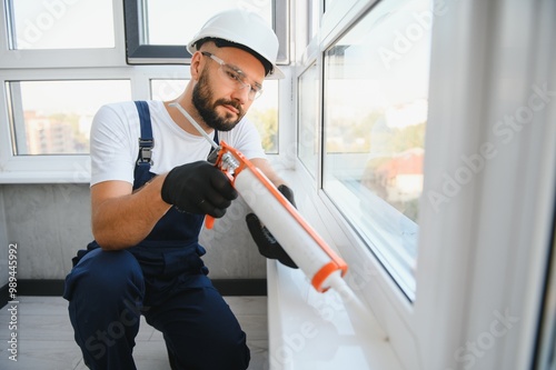 Obraz na plátně Worker sealing plastic window with caulk indoors