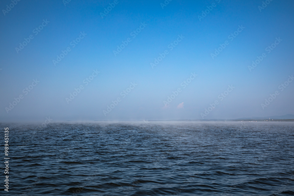 Fototapeta premium A vast body of water under a bright blue sky in the background