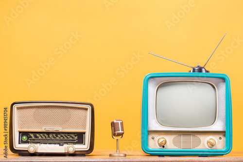 Retro radio, old TV and golden microphone front yellow background. Vintage style filtered photo