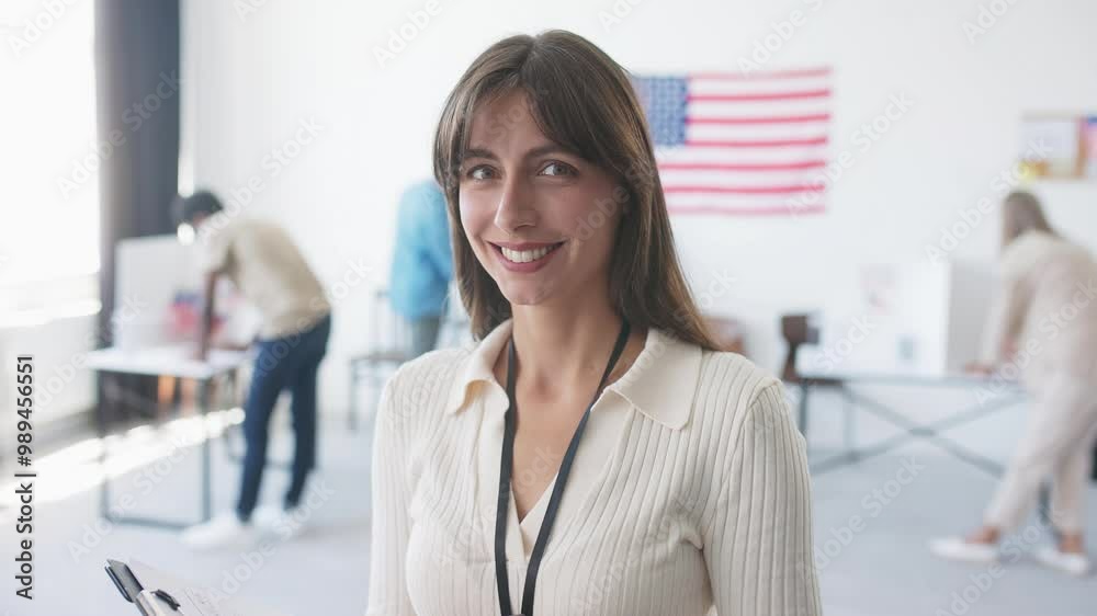 Attractive Caucasian woman standing in middle of polling station and holding notepad. Keeping track of people entering. Worker smiling with joy while looking directly at camera. People voting. Attractive Caucasian woman standing in middle of polling station and holding notepad. Keeping track of people entering. Worker smiling with joy while looking directly at camera. People voting.
