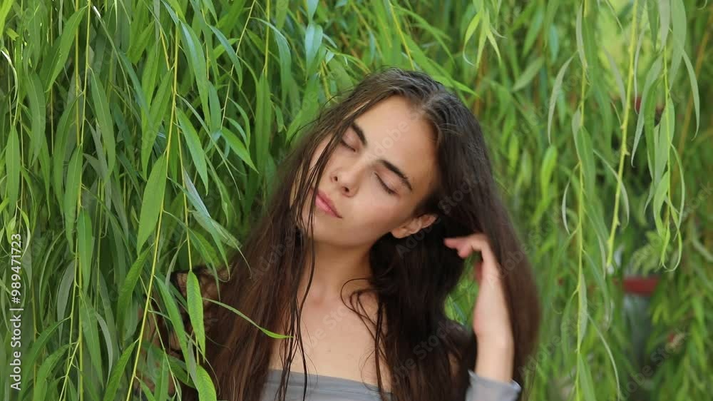 young beautiful brunette girl posing in willow foliage