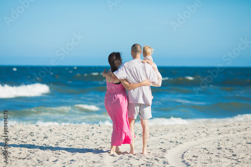 Happy parents carrying little doughter at beach