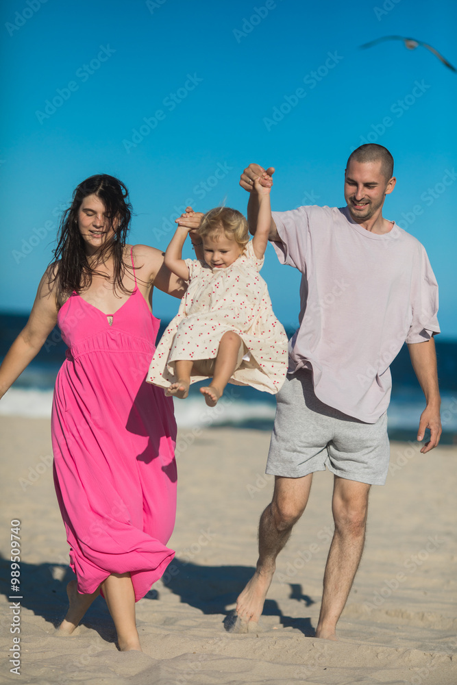Happy Family swinging and spinning cute daughter in circles by the arms at the beach. Playful, energetic and joyful kid having fun Happy Family swinging and spinning cute daughter in circles by the arms at the beach. Playful, energetic and joyful kid having fun